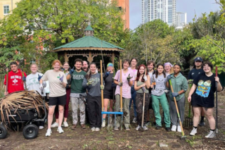 Students outside cleaning up garden area