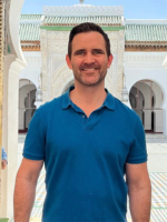 Man in blue shirt with white building in background