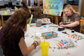 Two students making crafts at large table