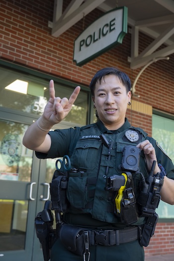 Police officer in front of station displaying the go bulls hand sign