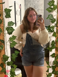 Student taking selfie in mirror covered in vines. 