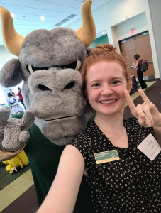 Student posing with Rocky the Bull making Bulls hand gesture