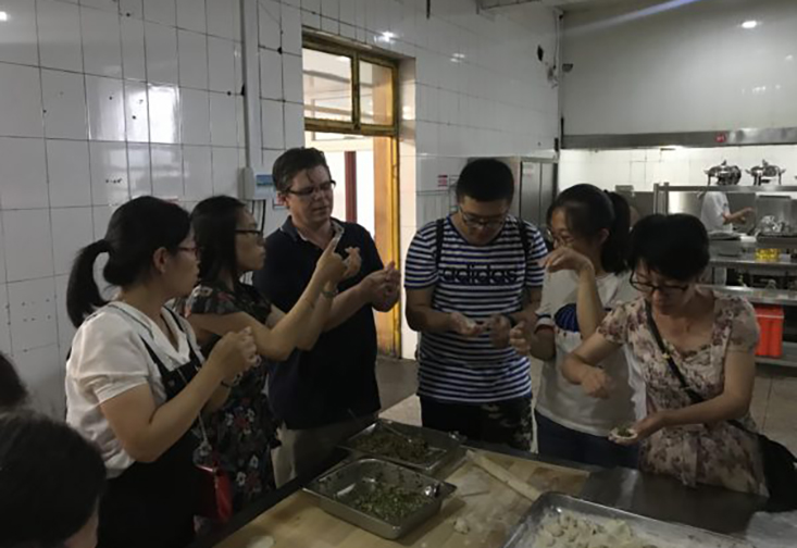 Chemistry Instructor John Osegovic not only taught students, but was taught by them, here learning how to make dumplings.