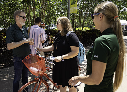 Guy Van Asten and Michelle Penn discuss campus cycling options with a student.