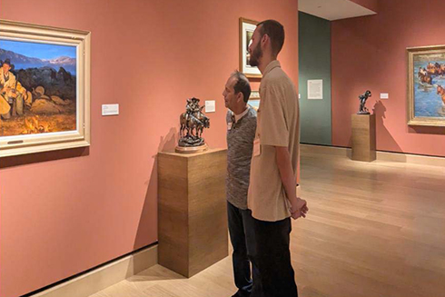 two males looking at artwork framed on wall