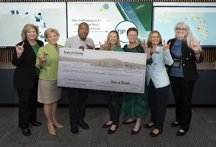 President Law with State Senator Rouson and State Representative Cross holding a ceremonial check.